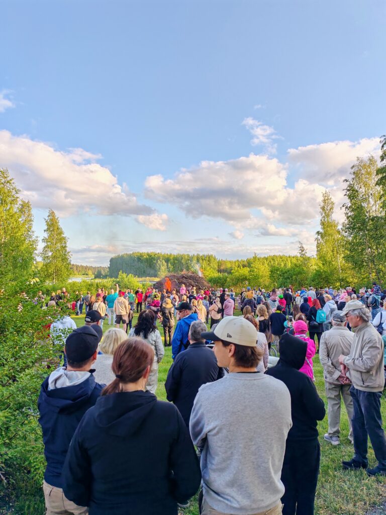 Kansaa siirtolapuutarhan juhannuskokkoa katselemassa