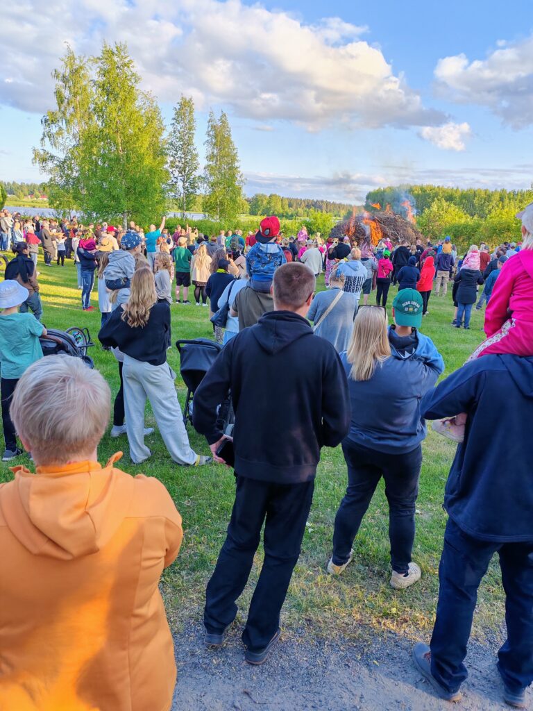 Kansaa siirtolapuutarhan juhannuskokkoa katselemassa